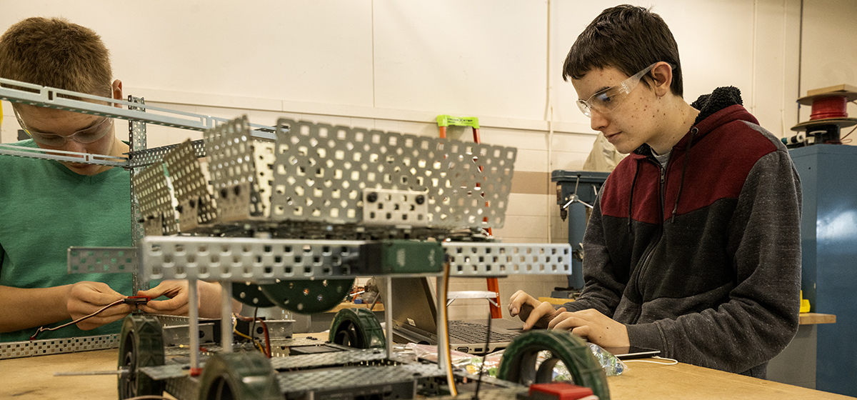 Two Engineering, Robotics, and Mechatronics students working on a robot