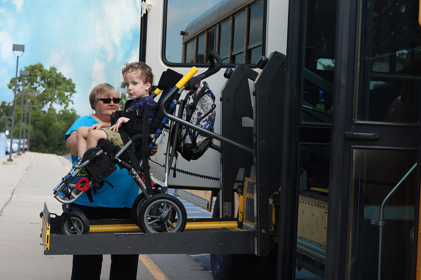 LISD employee helping student in wheelchair off school bus